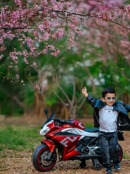 Capturing the adventurous spirit of a toddler is pure joy. This outdoor portrait session uses a fun toy motorcycle prop and the beautiful backdrop of spring blossoms to tell a story of childhood freedom and play.