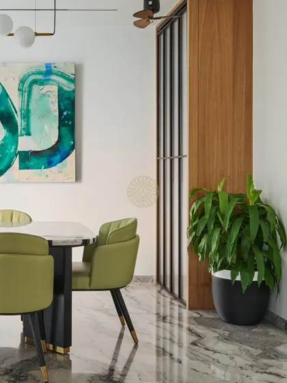 A view of the dining area showing the floating mandir with fluted sliding doors tucked into a corner. This design keeps the sacred space accessible yet discreetly integrated into the home's layout.