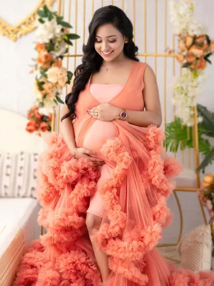 A beautiful solo portrait in the peach ruffled gown. The mother-to-be looks serene and radiant, surrounded by the soft, romantic layers of tulle.