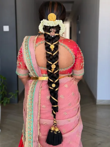 An intricate and traditional South Indian braid, woven with gold ribbons and adorned with classic temple-style hair jewelry.