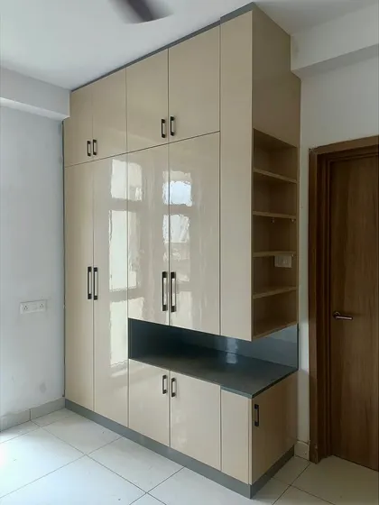 A completed project showcasing a floor-to-ceiling wardrobe in a neutral high-gloss laminate, with open shelving on the side for easy access.