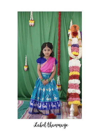 The little girl in her blue and pink langa blouse, posing against a festive background.