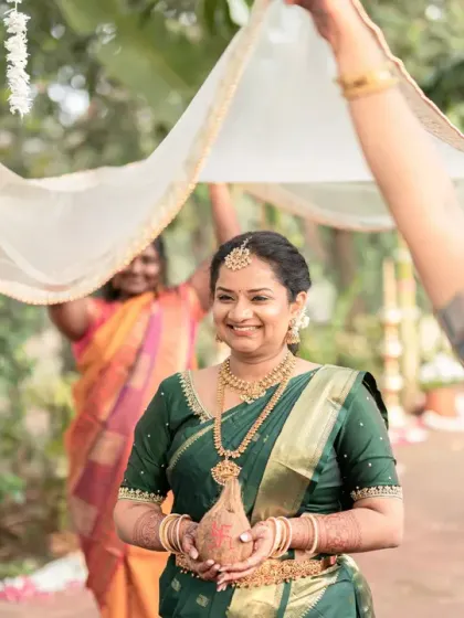 The bride's joyful entrance, walking under a sheer canopy held by the women in her family. Her radiant smile and the supportive presence of her loved ones make this a heartwarming shot.