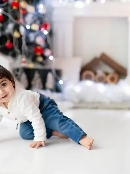 A little one exploring the magic of Christmas. Our festive setup with a tree and fireplace provides a cozy and cheerful backdrop for holiday photos.