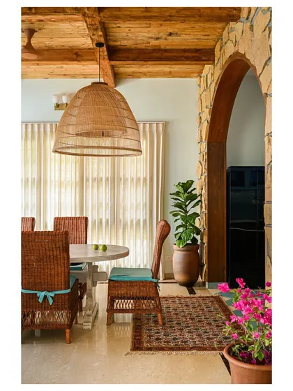 The dining area in "Far From The Stone Street," with its heavy wood-beamed ceiling, large cane chairs, and an arched entry to the kitchen.