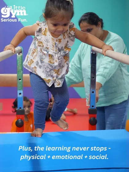 A toddler carefully walks across a balance beam with her mother's help, illustrating that the physical, emotional, and social learning never stops.