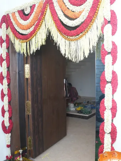 The main door of a new home, beautifully decorated with traditional flower garlands for a housewarming ceremony. This is the first thing guests see, and it sets a warm and welcoming tone.