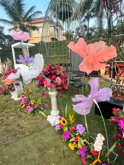 An aisle decorated with large, colorful paper flowers and birdcage props. These whimsical elements add to the fun and festive carnival theme of the Haldi.