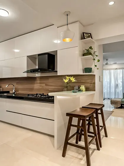 Here is a perfect example of an open-concept kitchen where a peninsula serves as a breakfast bar and a subtle divider from the living area. The clean white cabinets and wood-textured backsplash create a bright and airy feel.