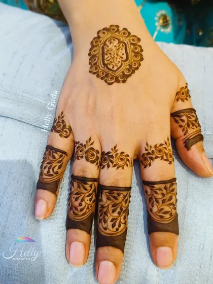 A unique and minimal design for a bride-to-be or her friends. This back-hand piece features a small, intricate crest on the palm with delicate floral bands on the fingers, leaving much of the hand open.