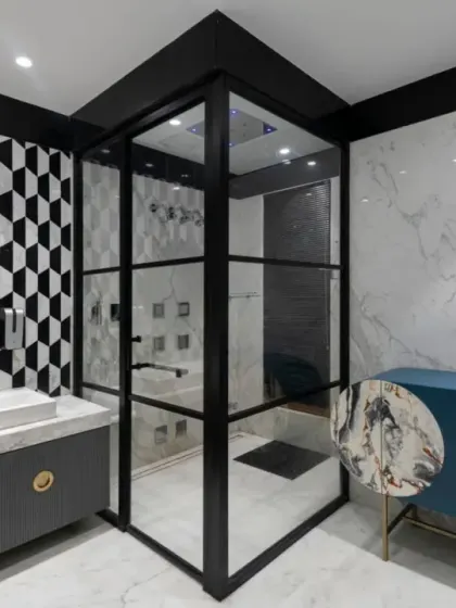 The parents' bathroom in the Screen House features a sleek modern white design, accented with striking black and white geometric splash tiles. It includes a well-appointed shower cubicle and a stylish blue cabinet.