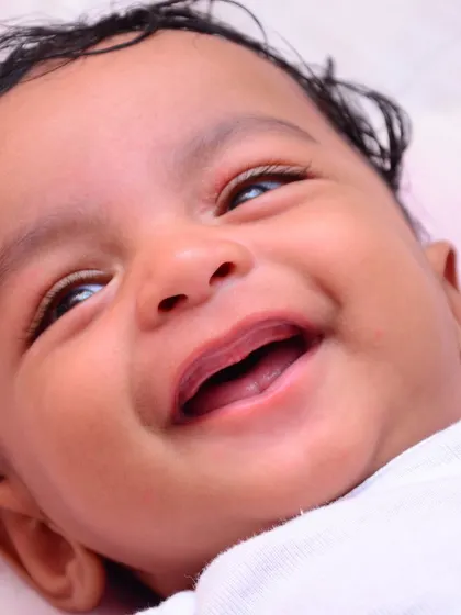 A joyful close-up capturing a baby's genuine, heartwarming smile. We focus on creating a relaxed atmosphere to capture these fleeting, precious expressions during our baby photoshoots.