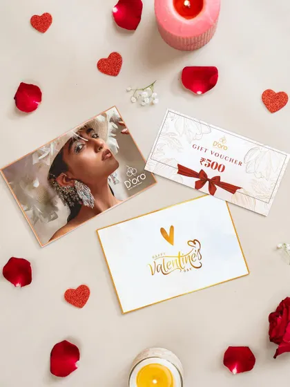 A close-up on the Valentine's Day gift cards and vouchers from the hamper shoot. The styling with rose petals and candles continues the romantic and celebratory theme.