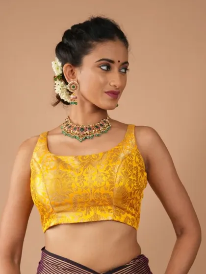 This model pairs a bright yellow brocade blouse with a multi-colored stone necklace, creating a vibrant and festive look.