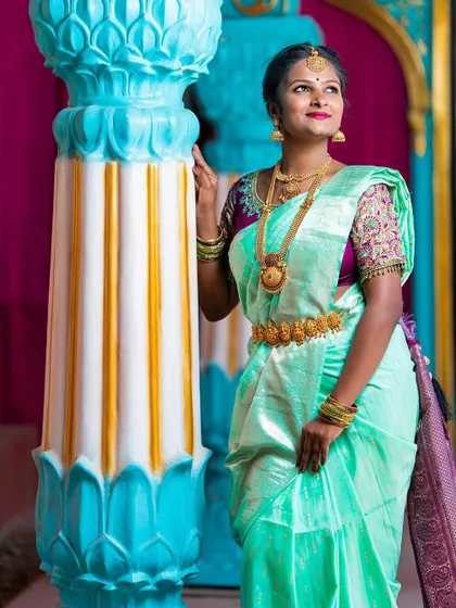 A beautiful portrait of the bride in her light green and purple silk saree, showcasing the rich colors of a South Indian wedding.