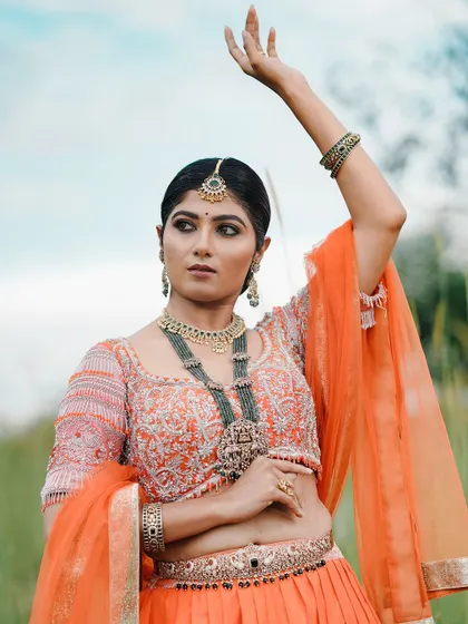 An outdoor portfolio shoot featuring a model in a beautiful orange lehenga, showing how makeup translates in natural light.