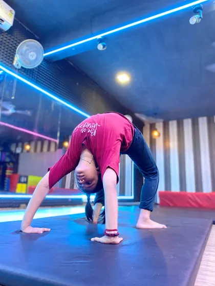 A student performs a perfect backbend on the mat. Notice the even arch in her back, which is a sign of good technique and consistent practice in our flexibility training sessions.