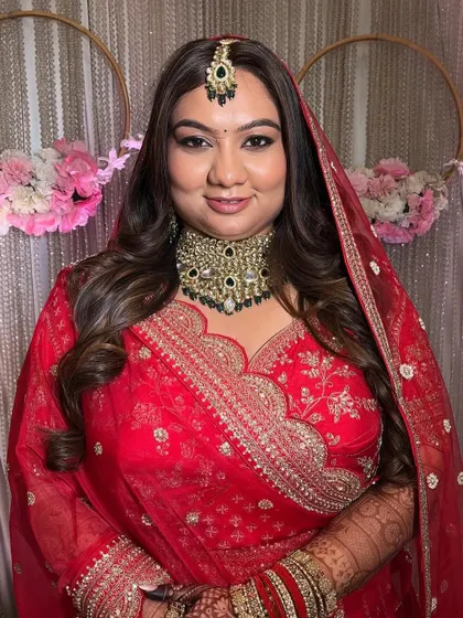 A full-length view of the bride in her magnificent red lehenga. The makeup is designed to complement the grandeur of her outfit, creating a cohesive and regal look.