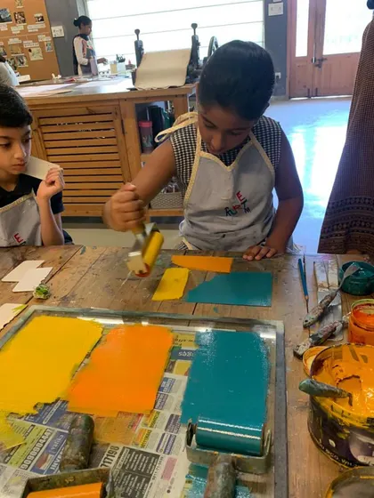 Learning about color and ink is a fun, hands-on part of our printmaking workshops. This young student is using a roller to apply vibrant colors to different plates for a monoprinting project.