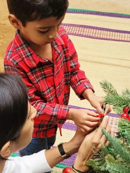 A child and adult decorate the Christmas tree together. We believe in celebrating festivals as a community, creating traditions and moments of connection that enrich our life at the school.