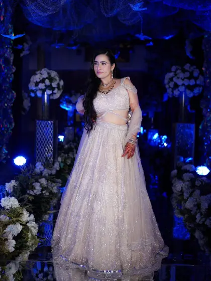 A stunning solo portrait of the bride in her shimmering sangeet lehenga, the dramatic blue lighting making her look like a star.