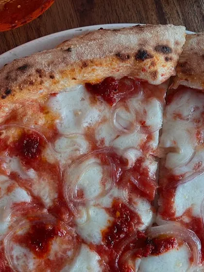 A close-up of the Goan Sausage pizza slice, showing the melted mozzarella and spicy sausage.