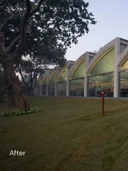 The "after" shot of the Okhla industrial shed, now a light-filled office space. The series of arched windows creates a beautiful rhythm along the building's length, connecting the interior workspace with the expansive lawn outside.