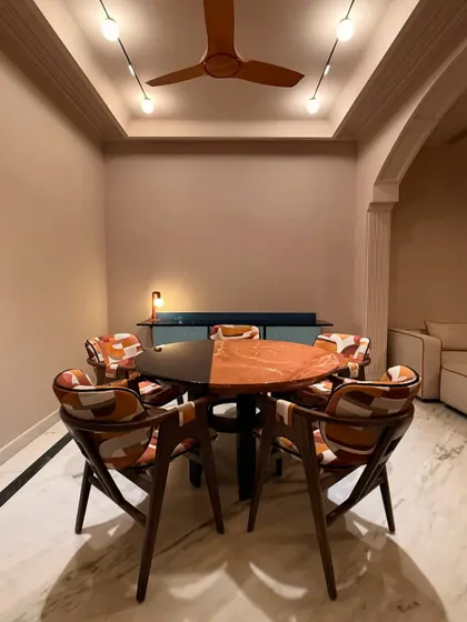 This dining set, named "Terra & Tide," was designed for a postmodern space that exudes boldness. The table features a striking split top of black and orange stone, while the chairs are upholstered in a vibrant, patterned fabric, all tied together with strong lines and colors.