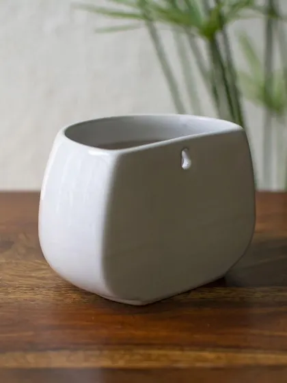 This perspective on the ceramic wall planter emphasizes its contemporary form. It's a perfect home for succulents, air plants, or small trailing vines, adding a touch of green to your wall decor.