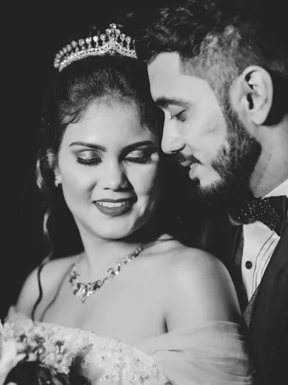 A tender black and white portrait of the couple. The low-key lighting creates a moody and romantic atmosphere, focusing on their faces.