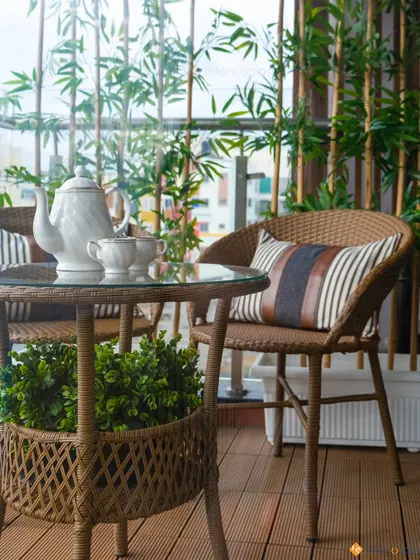 A cozy balcony setup with wicker furniture and bamboo plants for privacy. It's a serene little retreat perfect for enjoying a cup of tea.