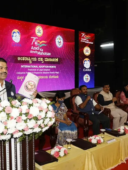 A speaker addresses the audience from a podium adorned with a large floral arrangement at the formal adoption awareness event we organized.