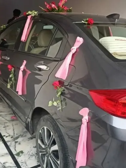A simple and elegant car decoration using pink roses and ribbons on the doors and roof.