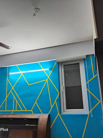 A different angle of the blue and yellow geometric accent wall, showing how it interacts with the room's lighting and furniture.