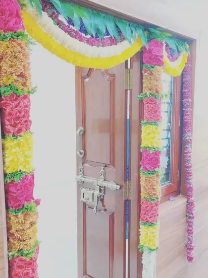 A close-up view of our traditional door decoration. We use fresh flowers like roses and marigolds to create these dense, colorful garlands that make the entrance feel special and welcoming.