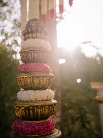 Traditional stacked brass pots adorned with flowers, used as decor elements in a classic South Indian wedding.