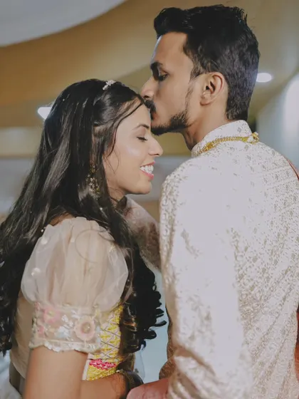 A gentle forehead kiss, capturing a tender moment during a pre-wedding ceremony.