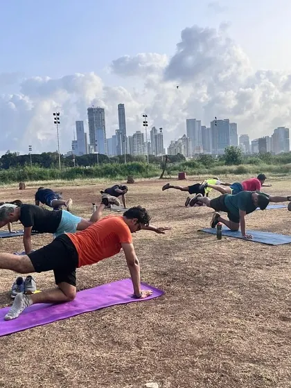 Our members working on their balance and core stability with bird-dog exercises at Mahalaxmi Racecourse, with the Mumbai skyline in the background.