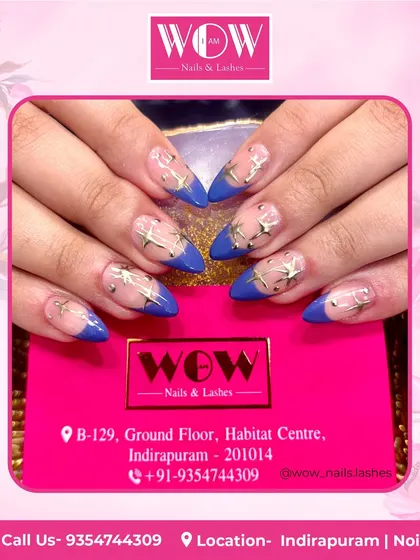 A bold and beautiful design featuring a deep blue French tip on a sheer base, adorned with golden star embellishments.