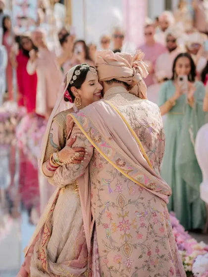 A heartfelt hug between the bride and groom after the ceremony, with guests capturing the moment in the background.