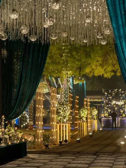 The grand entrance, where guests part the teal velvet curtains to enter the celebration. The ceiling is a cascade of crystals and disco balls, setting a party mood from the very beginning.