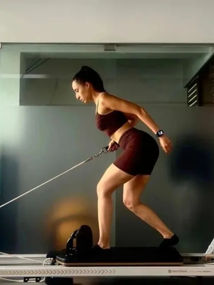 A client demonstrates a rowing variation on the Reformer. This exercise is excellent for strengthening the back and arms while challenging core control and posture.