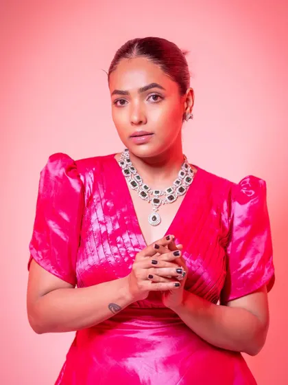 A close-up portrait showing the flattering V-neckline and pleated bodice of the pink gown.