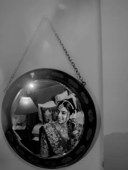 A black and white shot of the bride getting ready, captured in a mirror's reflection.