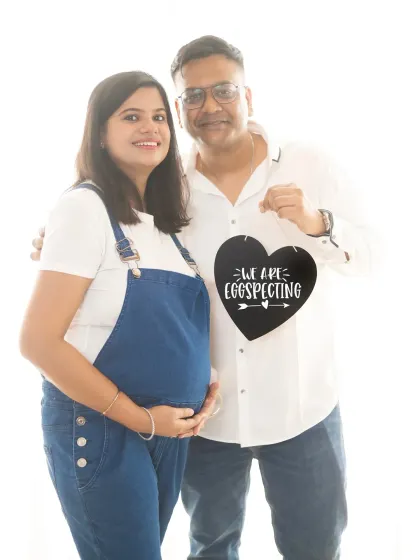 A classic announcement pose with a cute "We are egg-specting" sign. This couple's happy smiles make the photo extra special.