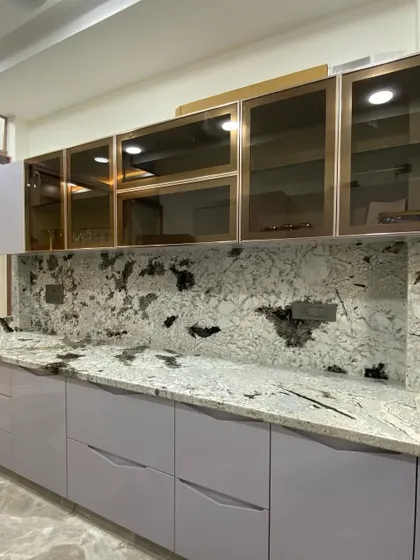 A work-in-progress shot of a kitchen with light purple cabinets and a dramatic granite countertop. This shows how we can work with bold and unique material choices.