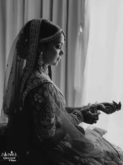 A dramatic black and white portrait of the bride by a window, using light and shadow to create a moody and timeless image.