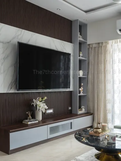 The television unit is often the centerpiece of a living room, and I design it to be a statement of style. This custom unit features a backlit Italian marble panel, handle-less drawers for a sleek look, and an integrated niche with a tinted mirror to display cherished art pieces.