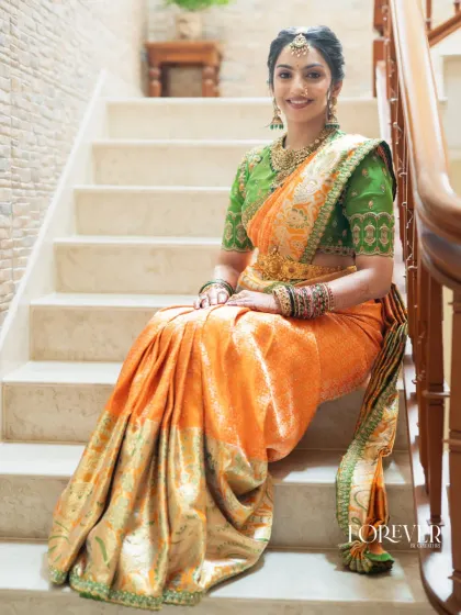 Seated gracefully, this bride showcases the beautiful drape of the orange Kanjivaram saree and the intricate embroidery on her green blouse. It’s a royal and elegant choice for a wedding ceremony.