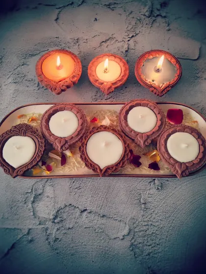 A tray of my Diya Candles, showing both the unlit white wax and the lit tri-color versions. These are poured into traditional terracotta diyas for an authentic feel.